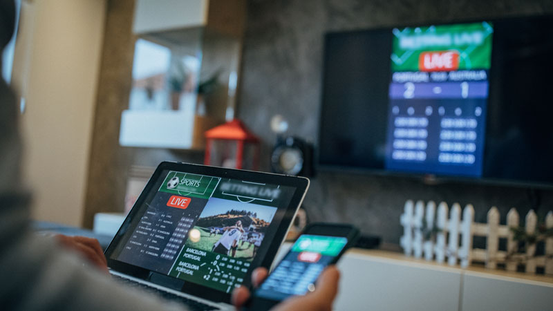 Pessoa a ver tv e a usar tablet e telemóvel